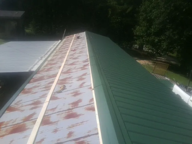 Old rusted panels beside newly installed green metal roofing — Wind Damage Roof Repair by Roofing Brothers in Mendota