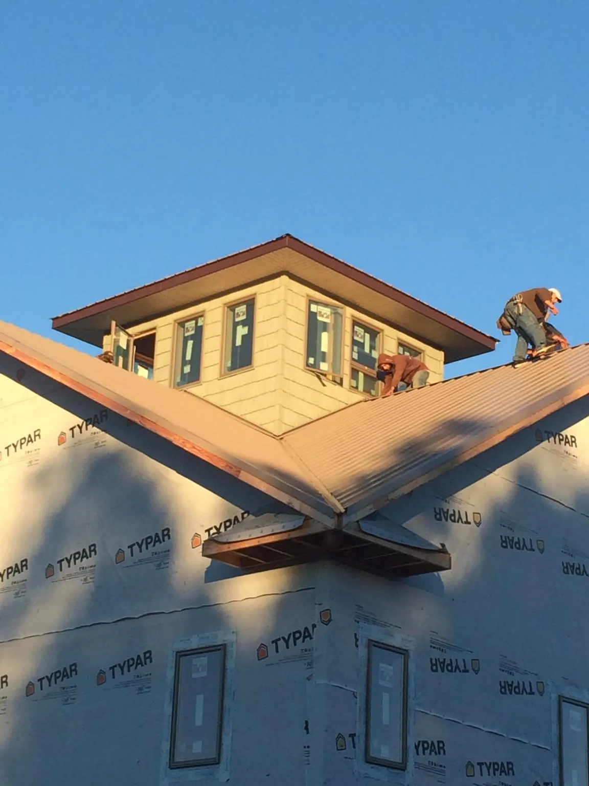 Roofers working around a rooftop cupola on a new metal roof at sunset — Roof Waterproofing in Mendota by Roofing Brothers